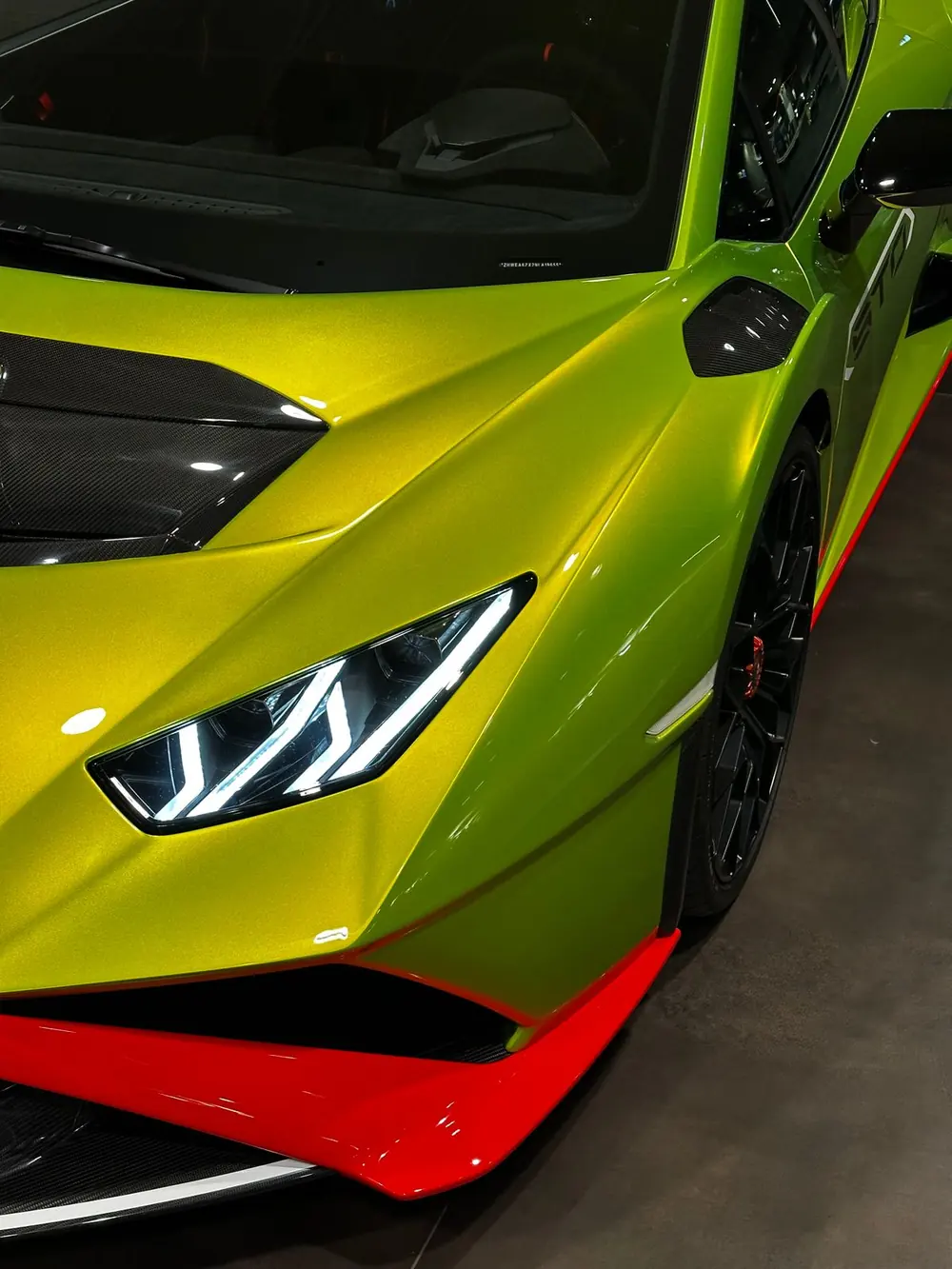 Close-up of a lime-green Lamborghini headlight and front splitter